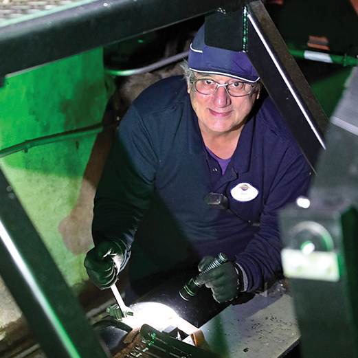 Ride & Show Technician examines electromechanical ride system for operational and guest safety