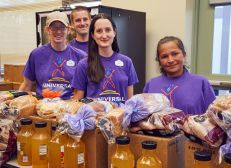 Group of Universal Orlando team members standing behind a table covered with boxes, breads, and bottled drinks