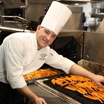 A culinary team member grilling carrots
