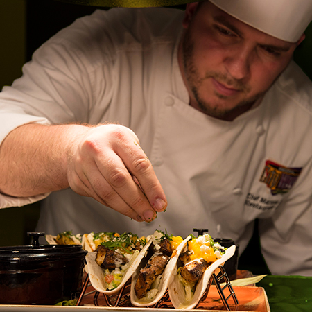 Culinary Team Member puts finishing touches on tacos