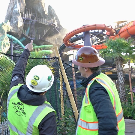 Two team members in construction hardhats looking up toward Volcano Bay