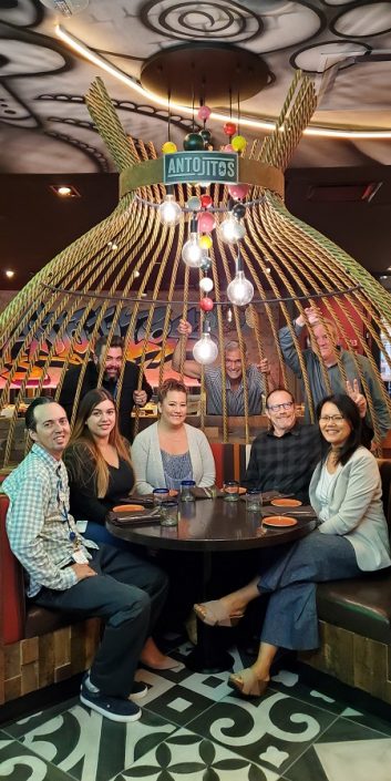 Team members seated and standing around a table booth at Antojitos
