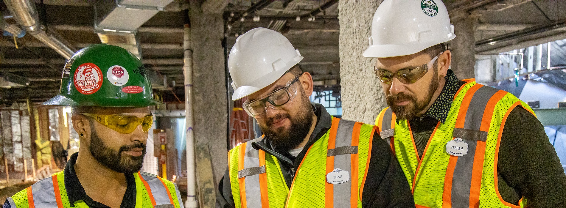 Three Universal Studios workers wearing PPE and huddling in the work field.