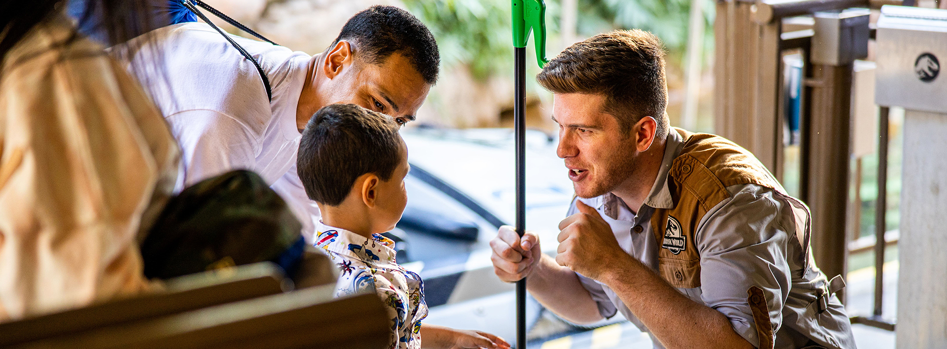 Universal Studios worker kneeling down and talking to a small child that is accompanied by an adult.