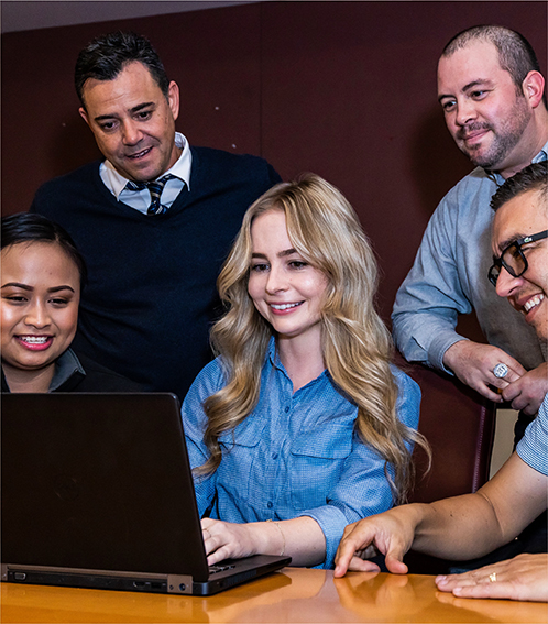 Five professional team members sitting around a laptop