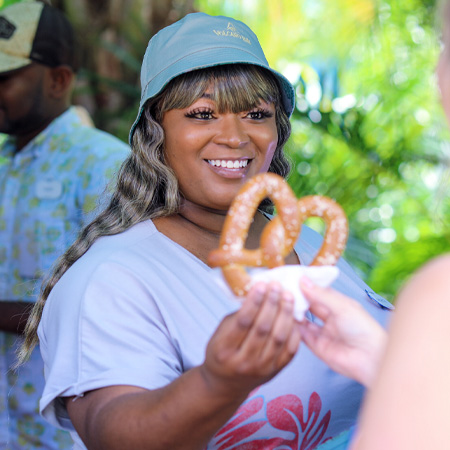 Volcano Bay Quick Service Team Member Handing a Guest a Pretzel