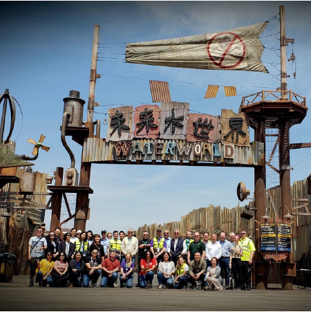 Group of Universal Creative Team Members standing under the Waterworld sign