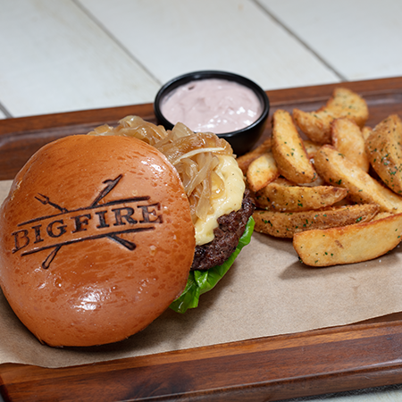 A burger sitting on a tray with fries and a dipping sauce beside it.