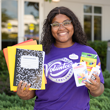 081425_School-Supply-Drive-Donation-Pickup_2284 Team Member holding up donated school supplies