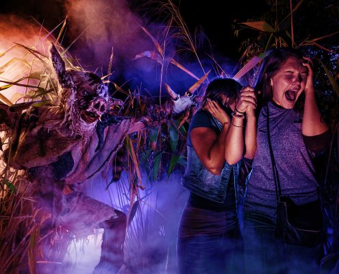 two girls being scared by a scare actor in a haunted house