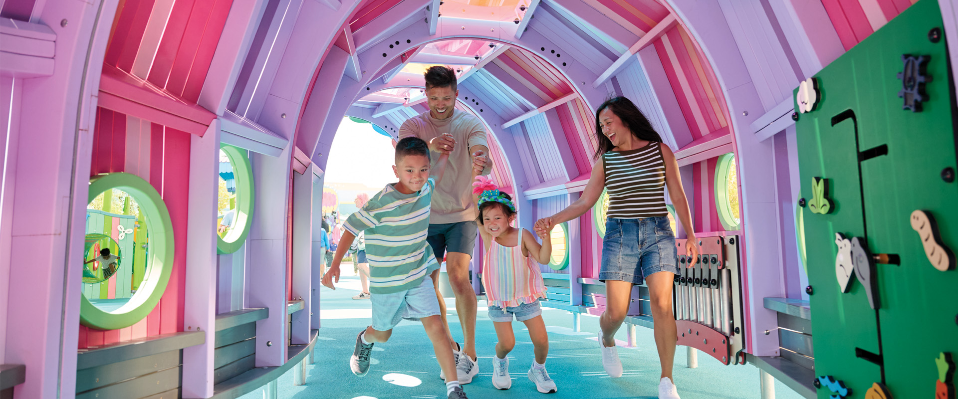Family running through playground, two adults and two children