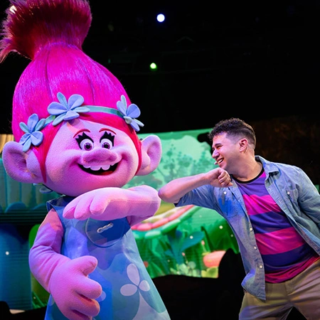 A Team Member gives Princess Poppy from Trolls an elbow bump