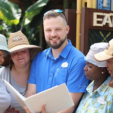 Group of Team Members at Volcano Bay looking at a document with their Manager who is looking at the camera while smilig